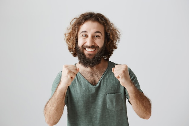 Soddisfatto uomo mediorientale che alza i pugni, celebrando il successo e la vittoria