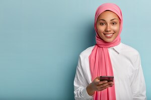 免费的照片高兴穆斯林妇女使用手机进行社交活动,给予回复在网上聊天,文章在社交网络上的东西