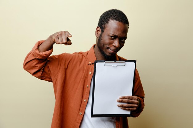 Pleased points at camera young african american male holding clipboard isolated on white background