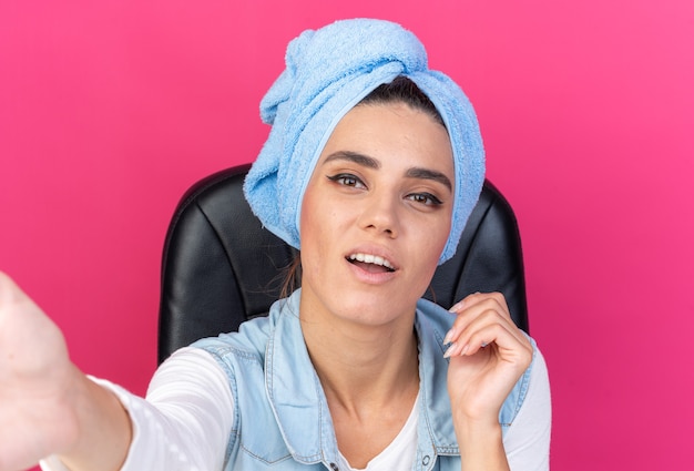 Pleased pretty caucasian woman with wrapped hair in towel sitting at table