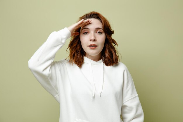 pleased showing salute young female wearing white sweater isolated on green background