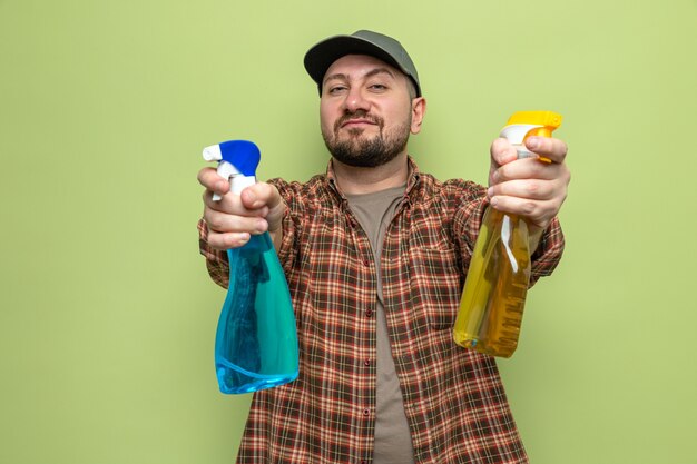 Pleased slavic cleaner man holding spray cleaners