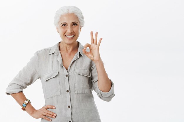 Pleased smiling old lady showing okay gesture in approval, recommend company, like idea