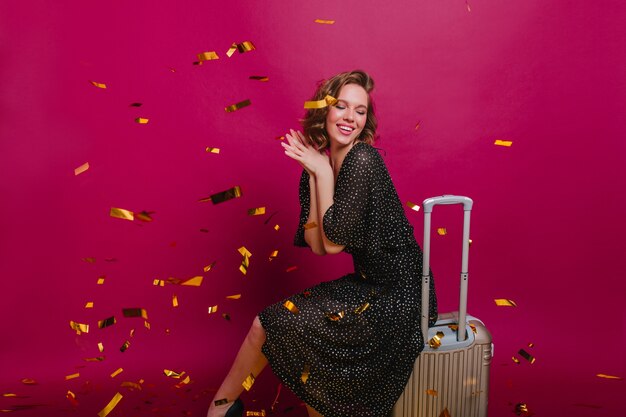 Pleased stylish lady dreamy posing on purple background before upcoming trip