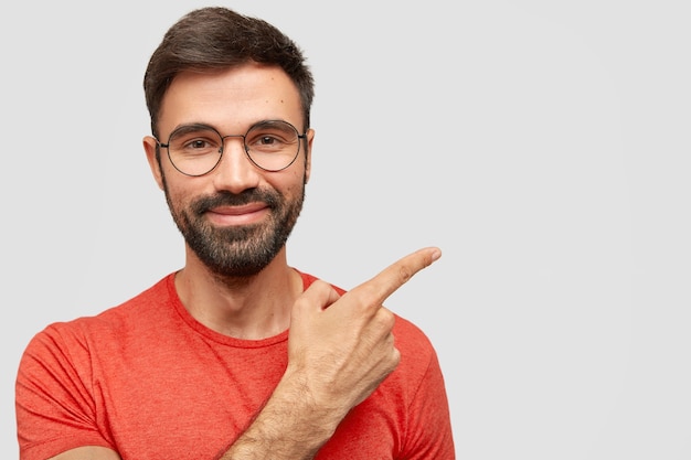 Soddisfatto uomo europeo con la barba lunga dall'espressione allegra, ha una folta barba incolta, punta di lato