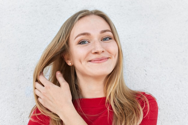 Pleased woman with blonde hair, luminous eyes and gentle smile having dimples on cheeksl