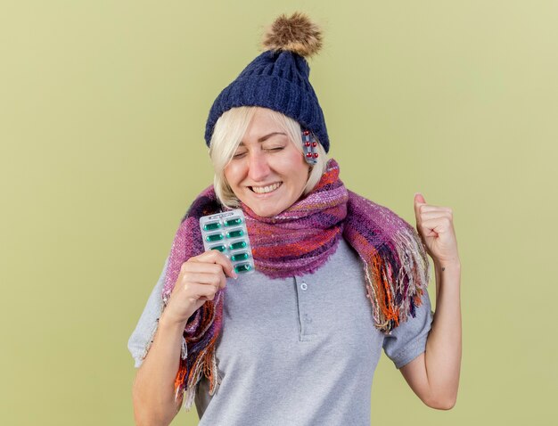 Free photo pleased young blonde ill slavic woman wearing winter hat