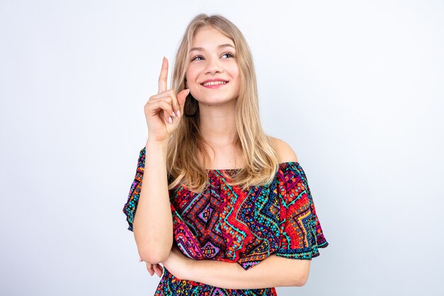 Pleased young blonde woman pointing up 
