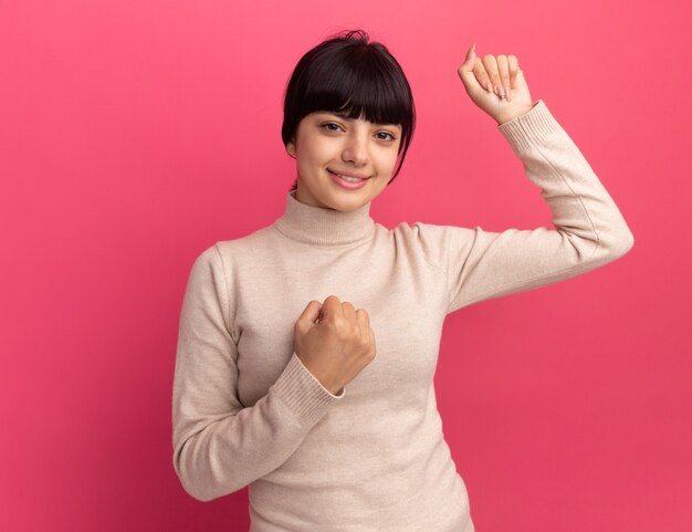 Pleased young brunette caucasian girl keeps fists