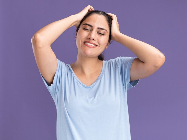 Pleased young brunette caucasian girl puts hands on head