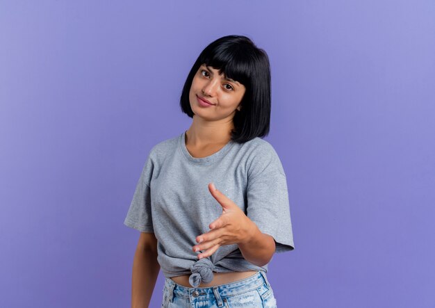 Pleased young brunette caucasian woman holds hand out