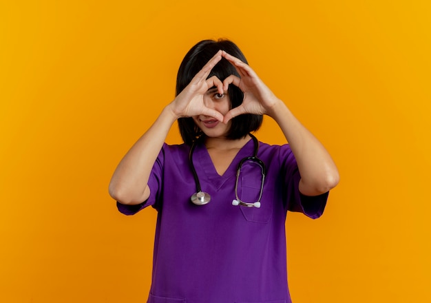 Lieta giovane dottoressa bruna in uniforme con stetoscopio