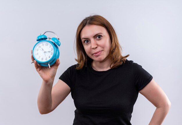 Pleased young casual woman holding alarm clock on isolated white space