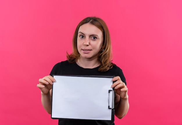 Pleased young casual woman holding clipboard on isolated pink space with copy space