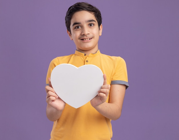 Pleased young caucasian boy holding heart shape 