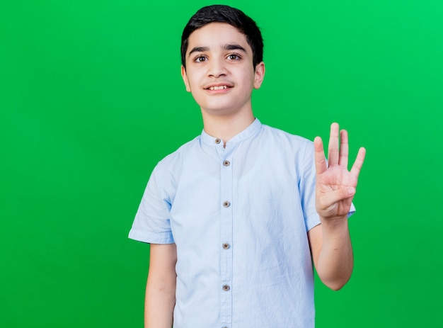 Free photo pleased young caucasian boy looking at camera showing four with hand isolated on green background with copy space