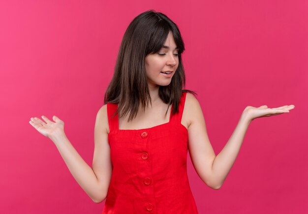 Pleased young caucasian girl holds hands up on isolated pink background