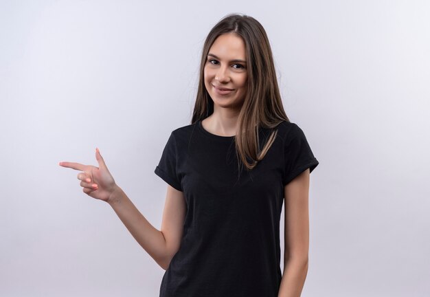 pleased young caucasian girl wearing black t-shirt points to side on isolated white wall