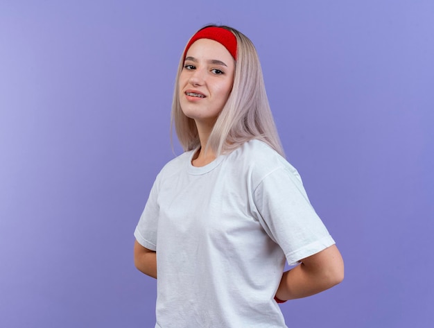 Free photo pleased young caucasian sporty girl with braces wearing headband