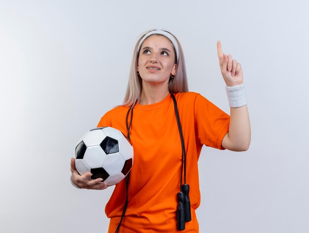 Pleased young caucasian sporty girl with braces and with jumping rope around neck