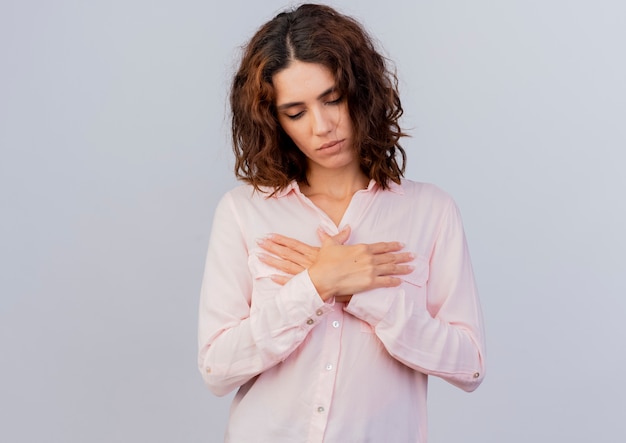 Foto gratuita la giovane donna caucasica soddisfatta incrocia le mani e si mette sul petto