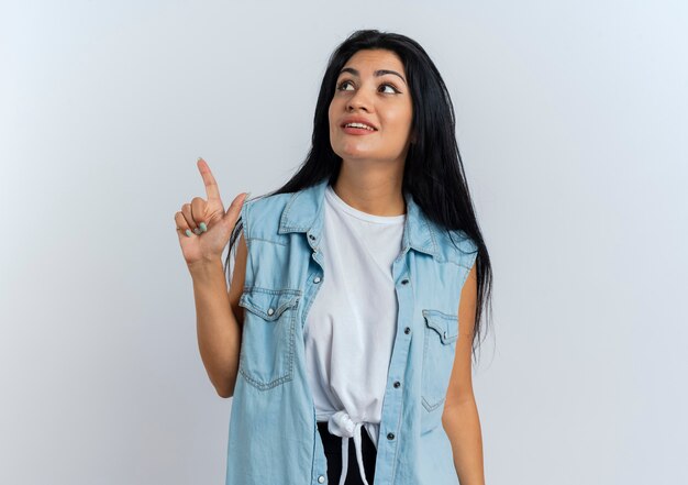 Pleased young caucasian woman looks and points up