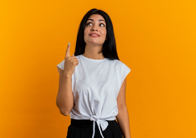 Pleased young caucasian woman looks and points up