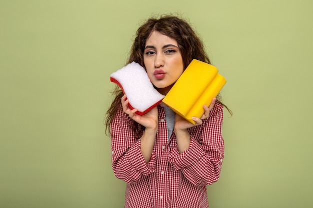 Free photo pleased young cleaning woman holding cleaning sponges around face