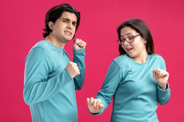 Pleased young couple on valentines day dancing isolated on pink background