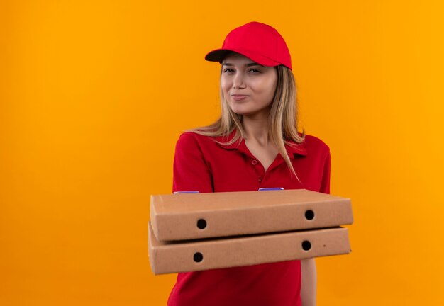 빨간 유니폼과 모자를 입고 기쁘게 젊은 배달 여자 피자 상자를 들고