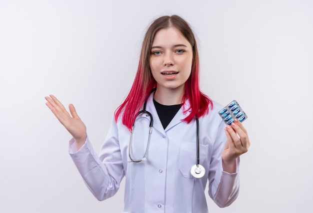 Foto gratuita felice giovane medico ragazza indossa stetoscopio abito medico azienda pillole diffusione mano su sfondo bianco isolato