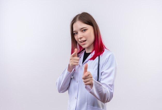 孤立した白い背景の上のジェスチャーを示す聴診器医療ローブを身に着けている若い医者の女の子を喜ばせる