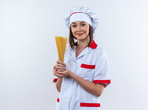 Pleased young female cook wearing chef uniform holding spaghetti isolated on white background