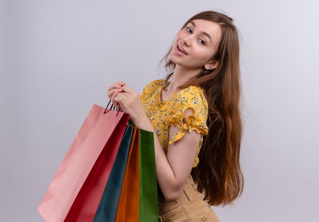 Pleased young girl holding paper bags standing in profile view 