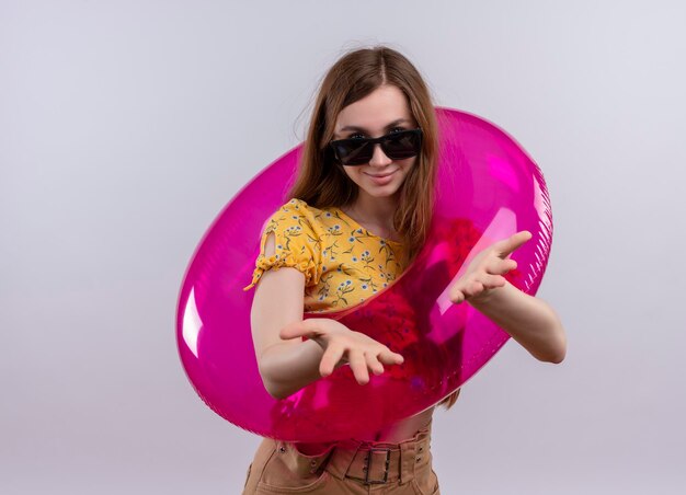 Pleased young girl wearing sunglasses and swim ring showing empty hands on isolated white space with copy space