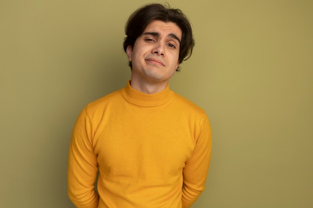 복사 공간 올리브 녹색 벽에 고립 된 노란색 터틀넥 스웨터를 입고 기쁘게 젊은 잘 생긴 남자