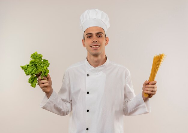 Довольный молодой мужчина-повар в униформе шеф-повара держит спагетти и салат
