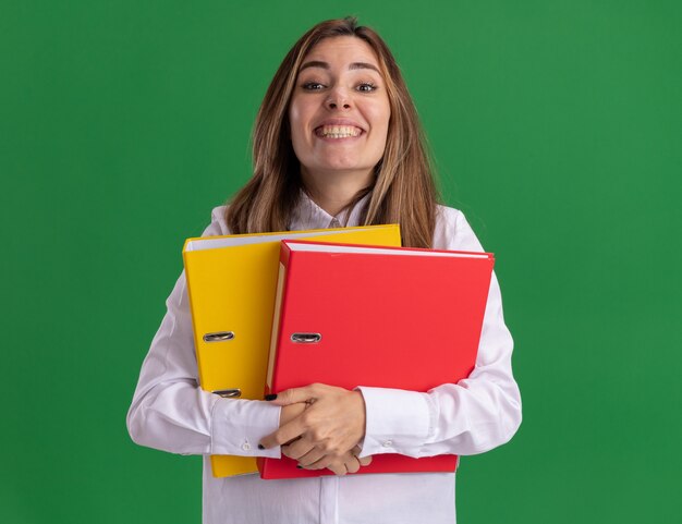 Pleased young pretty caucasian girl holds file folders on green 