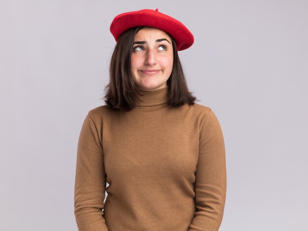Pleased young pretty caucasian girl with beret hat looking at side on white
