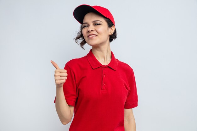 Pleased young pretty delivery woman thumbing up