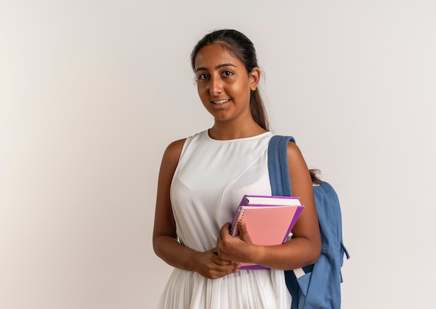 Довольная молодая школьница в задней сумке, держащая ноутбук на белом