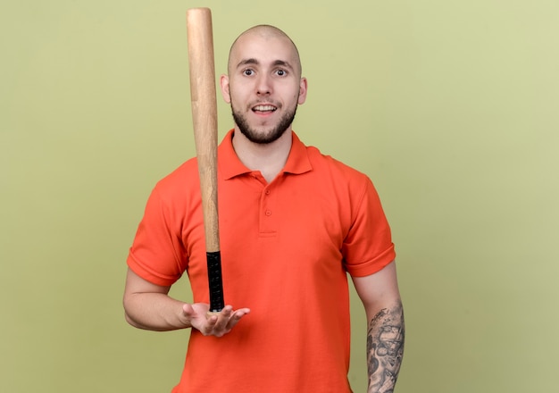 Free photo pleased young sporty man holding beisbol bit on palm isolated on olive green wall