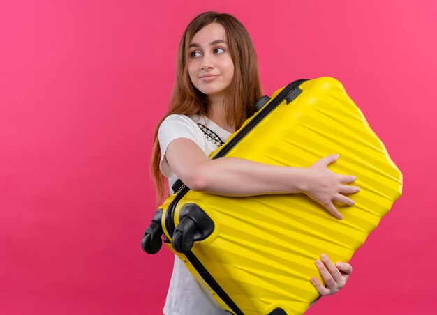 행복 한 젊은 여행자 소녀 가방을 들고 복사본 공간이 격리 된 분홍색 공간에 왼쪽을보고