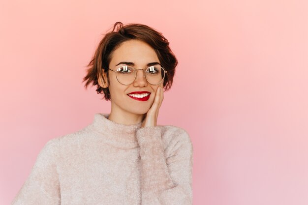 Pleased young woman in glasses touching face