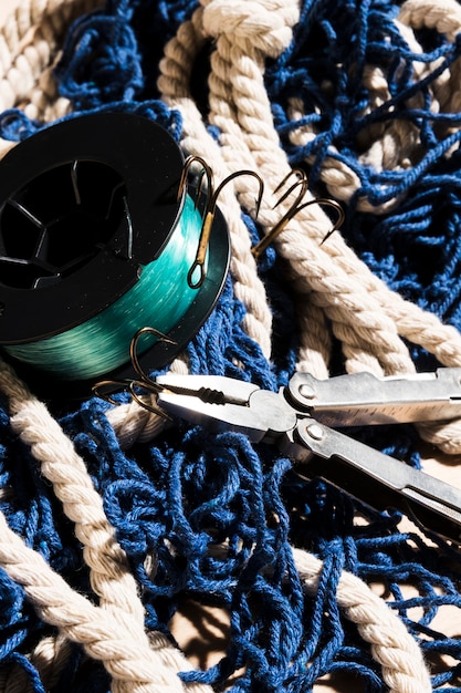 Plier and fishing hooks on blue fishing net