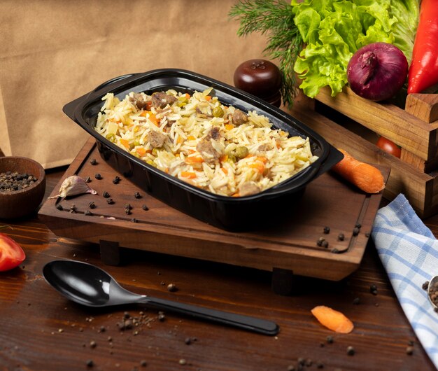 Plov, rice garnish with vegetables, carrots, chestnuts and beef pieces takeaway   