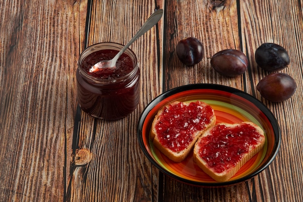 Plum confiture in the glass jar and on the toast.