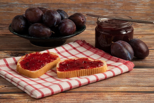 Plum confiture on the toast on the checked towel.