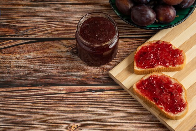 Plum confiture on the toast on the wooden board.