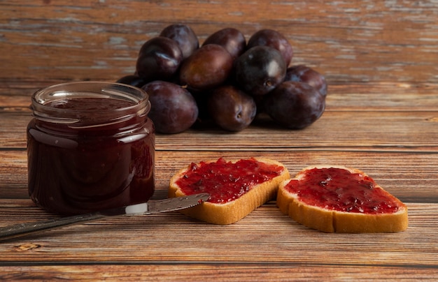 Plum confiture with toast breads and fruits on a wooden table.